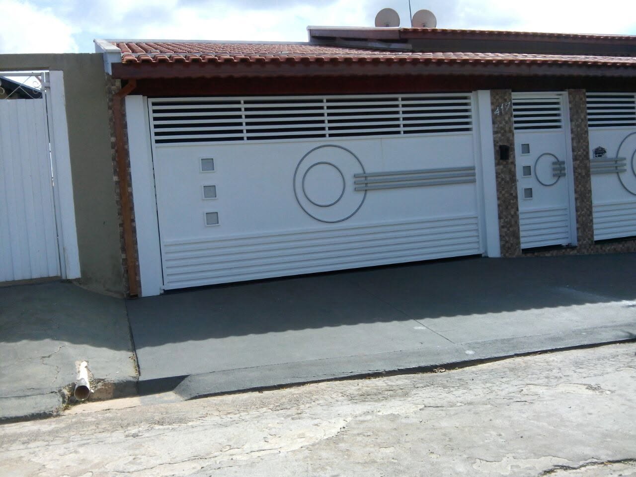 Portão de garagem com desenho circular e porta social, entregue em Mococa